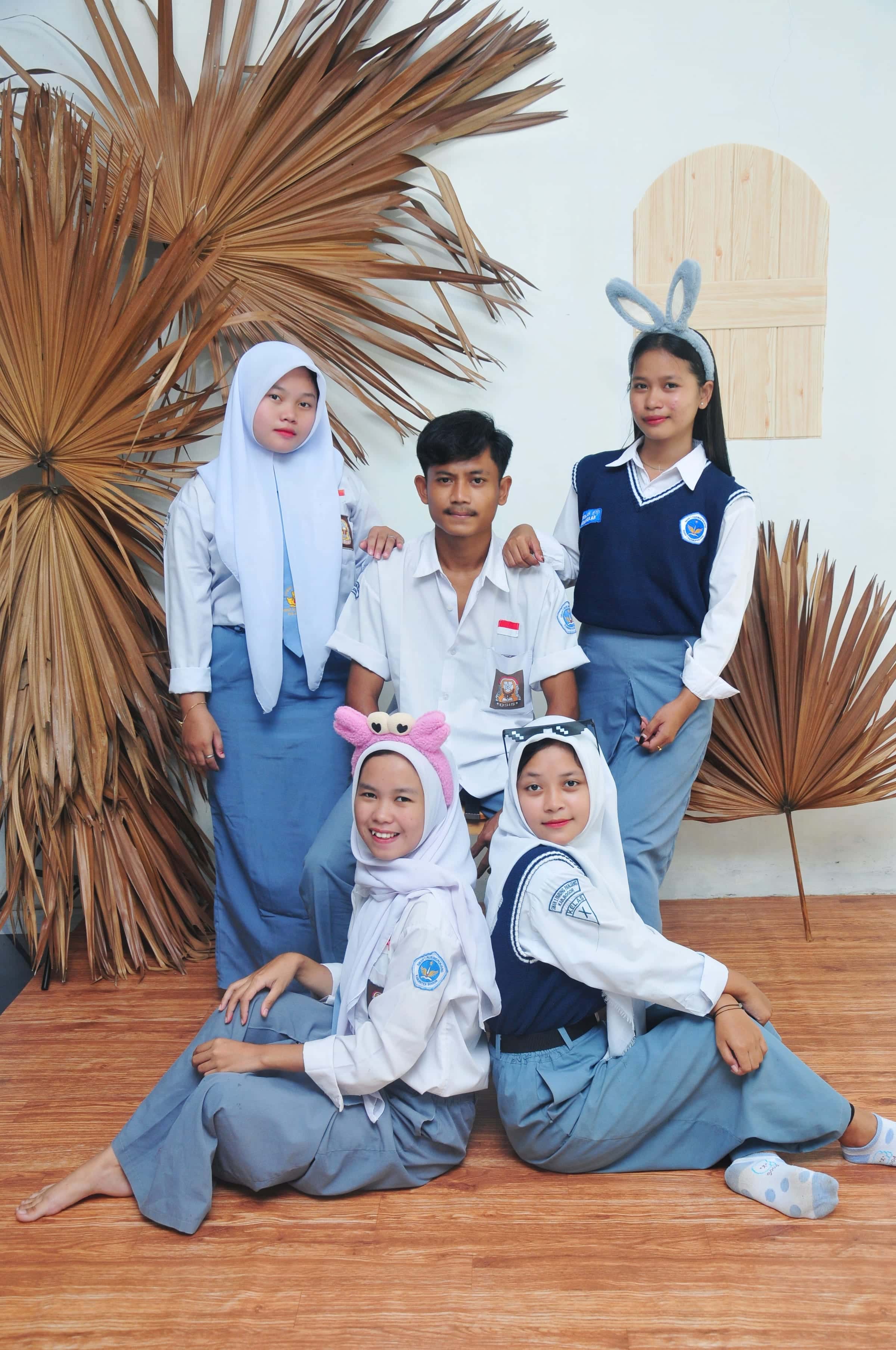 Foto event grup pelajar dengan latar dekorasi daun kering