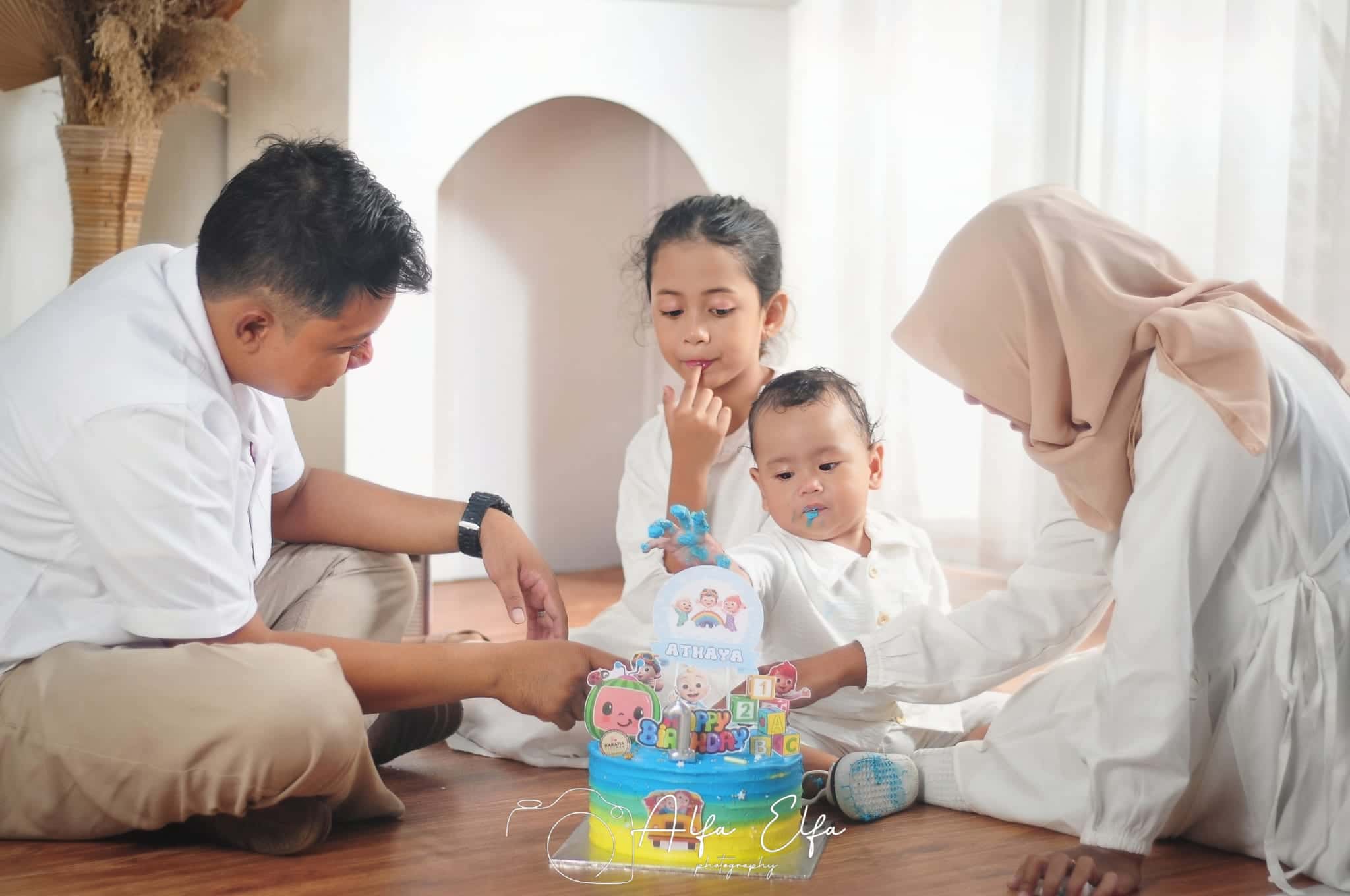 Foto keluarga kecil merayakan ulang tahun anak dengan kue