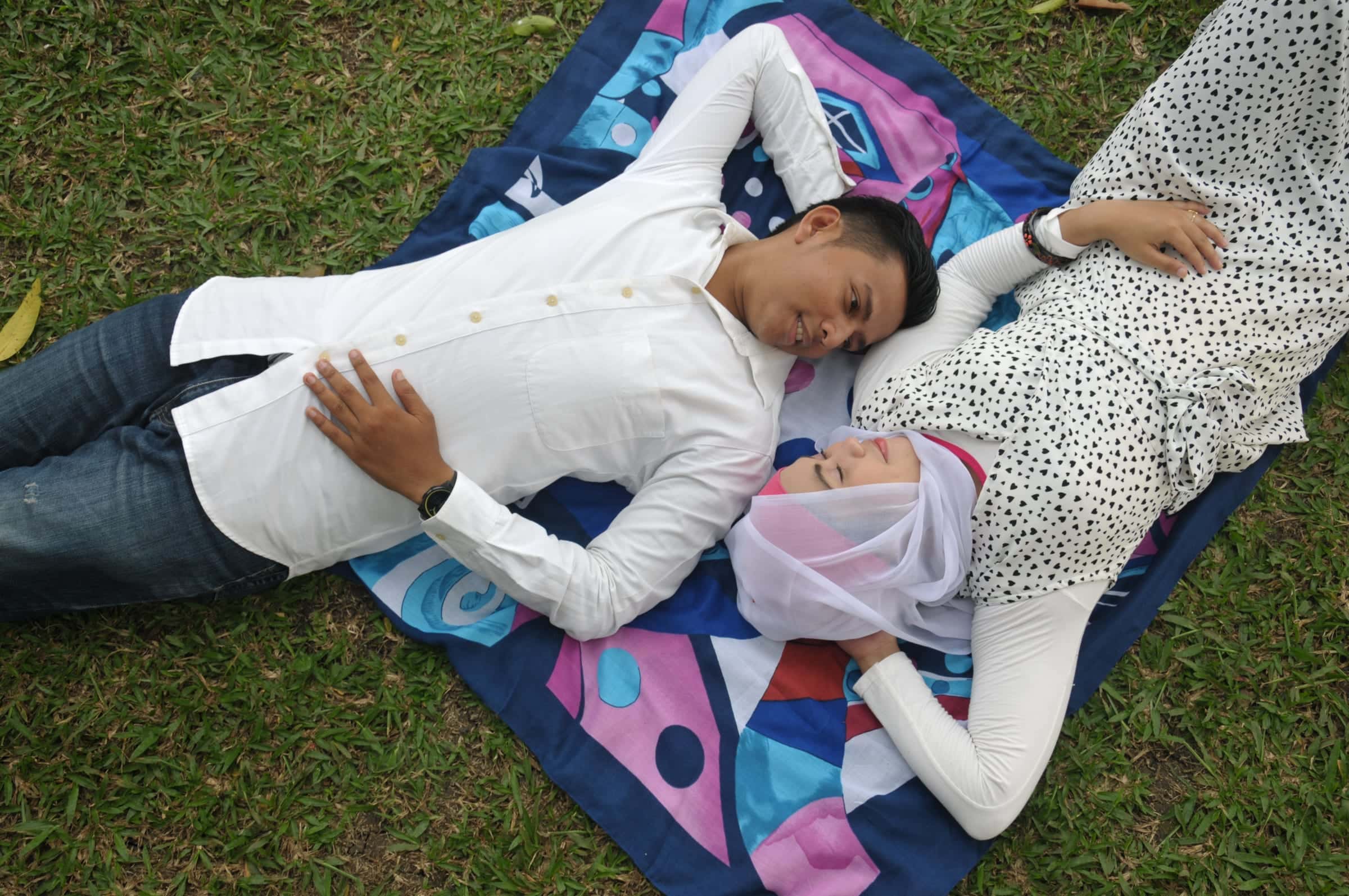 Foto keluarga dua anak bermain santai di atas alas tikar berwarna