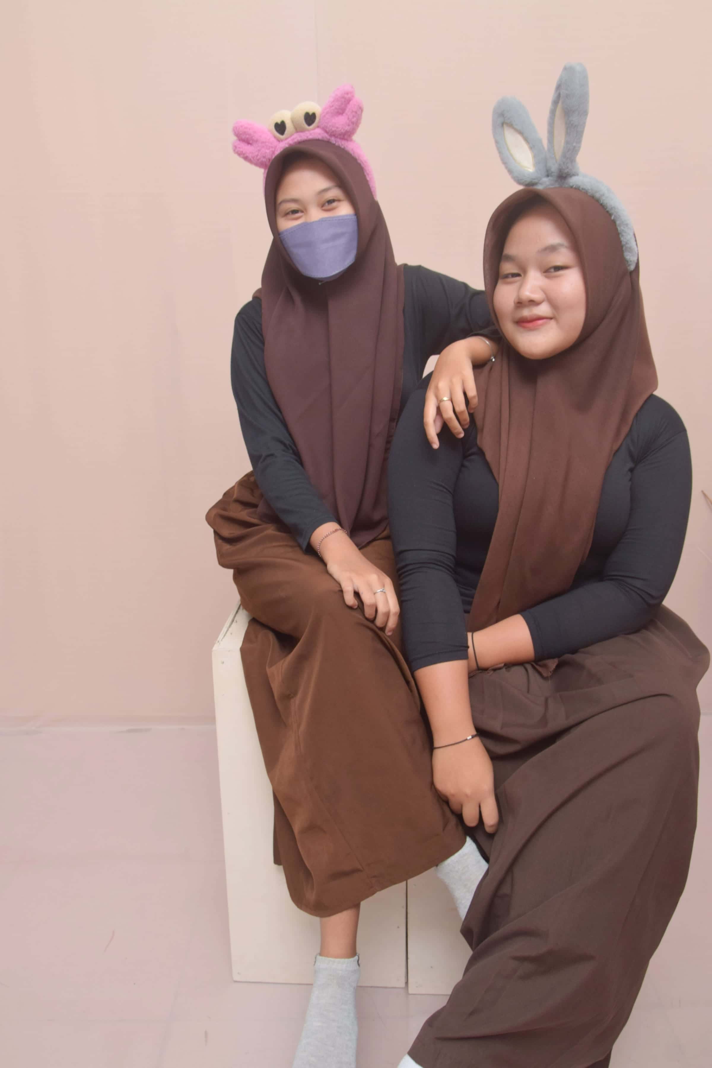 Foto keluarga ibu dan anak duduk santai busana cokelat