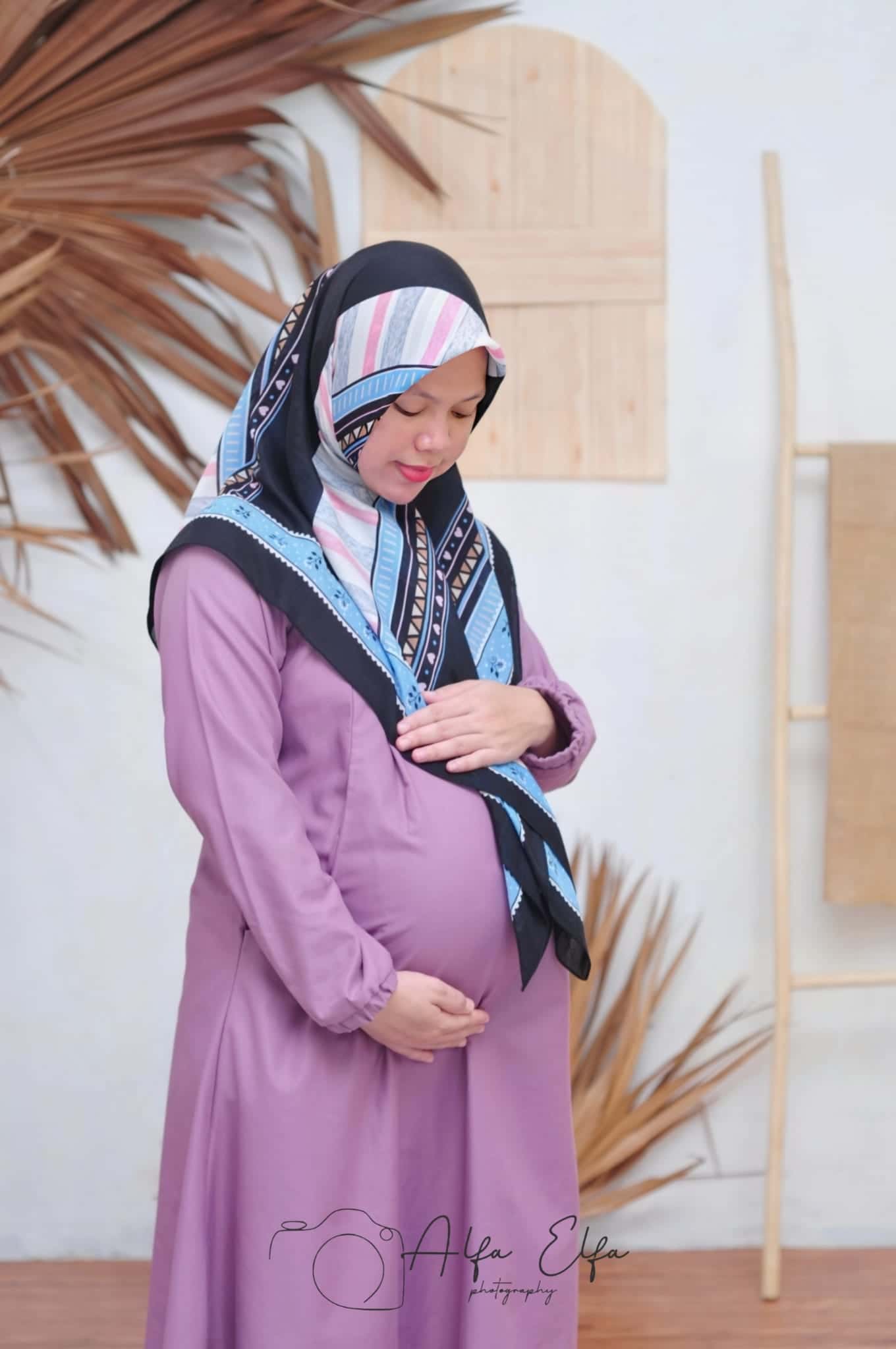 Foto maternity ibu hamil tampak samping busana ungu elegan