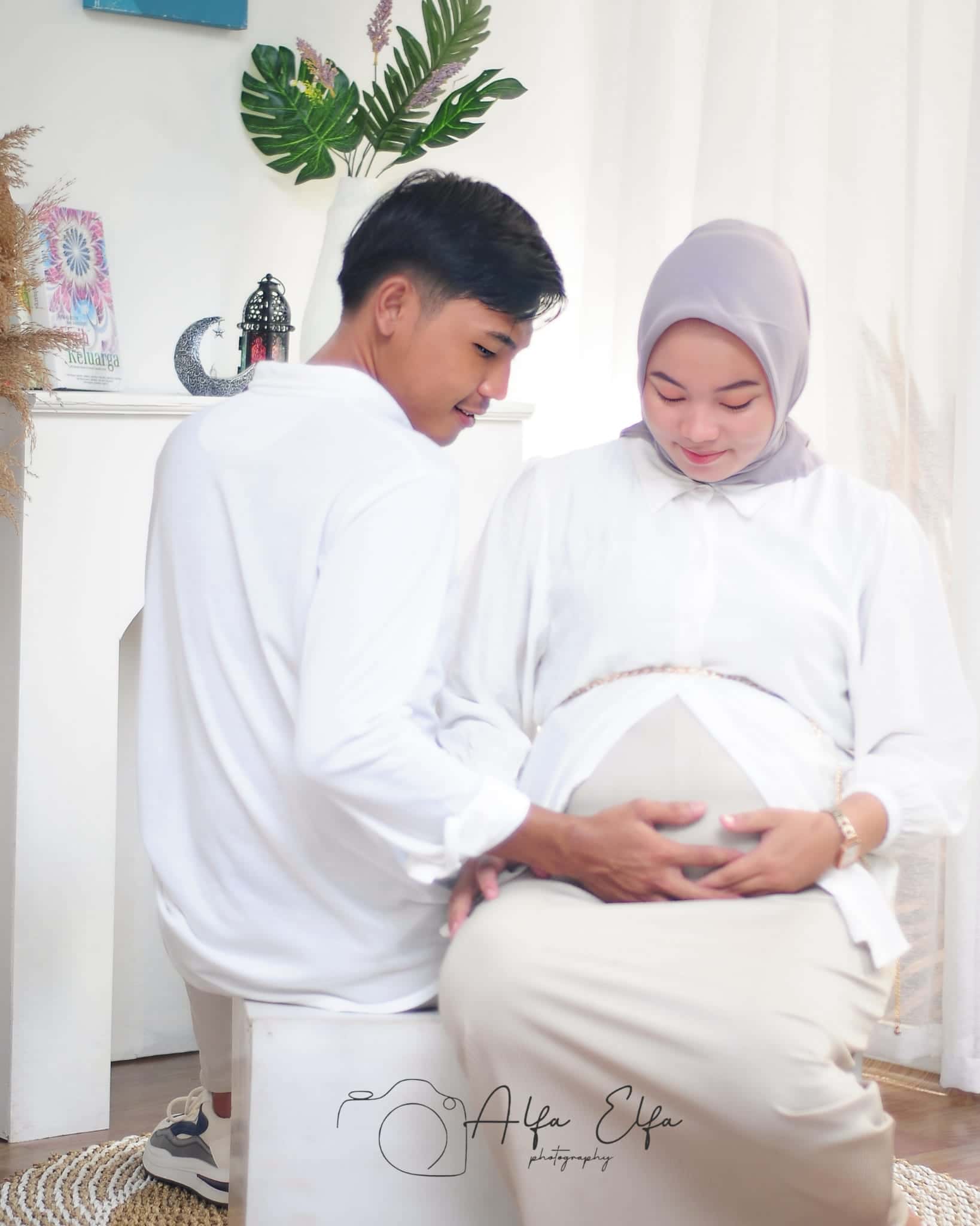 Foto maternity pasangan busana putih memegang perut kehamilan