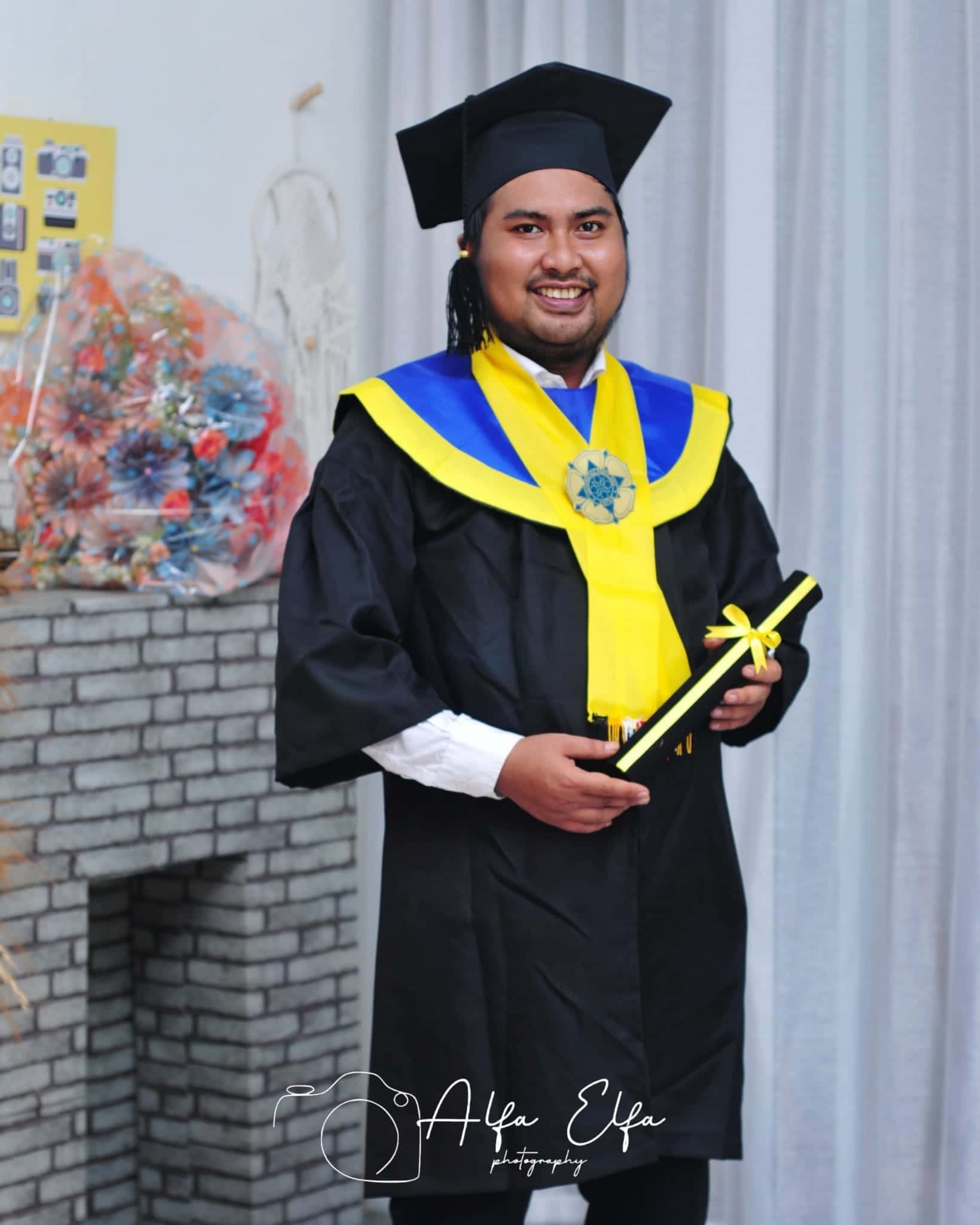 Foto wisuda pria toga dengan selempang kuning hijau kelulusan